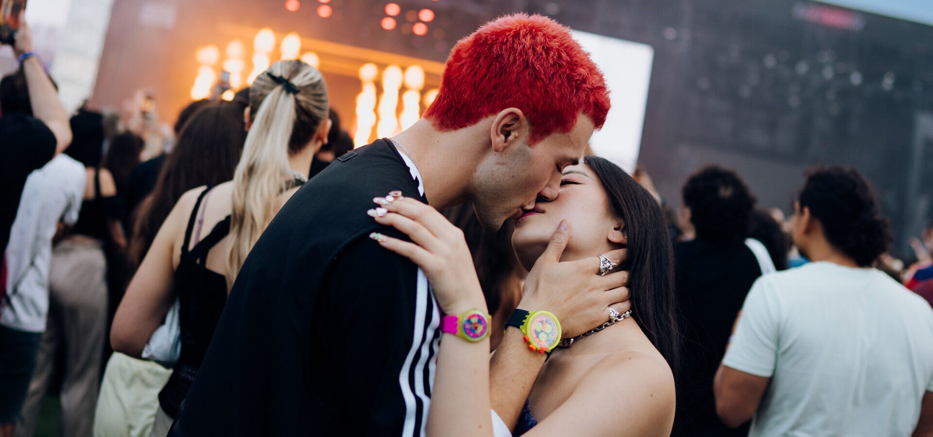 A young couple kissing in the festival crowd 