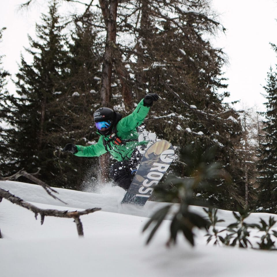 Xavier De Le Rue jumping in powder snow on his snowboard