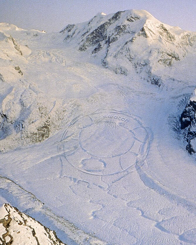 A giant Swatch carved in snow for the launch campaign of Swatch Beat Aluminium, a Swatch displaying different time zones as well as the internet time in "Beats", 1999