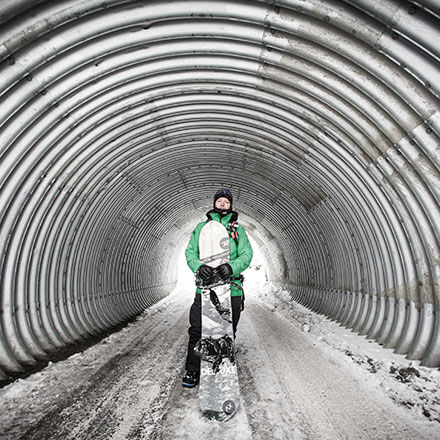 Xavier De Le Rue standing a tunnel with his snowboard