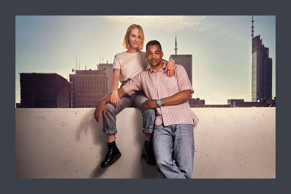 Couple sitting on a wall with city background 