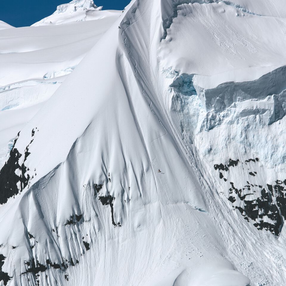 Xavier De Le Rue freeriding down a mountain summit, full view of the landscape