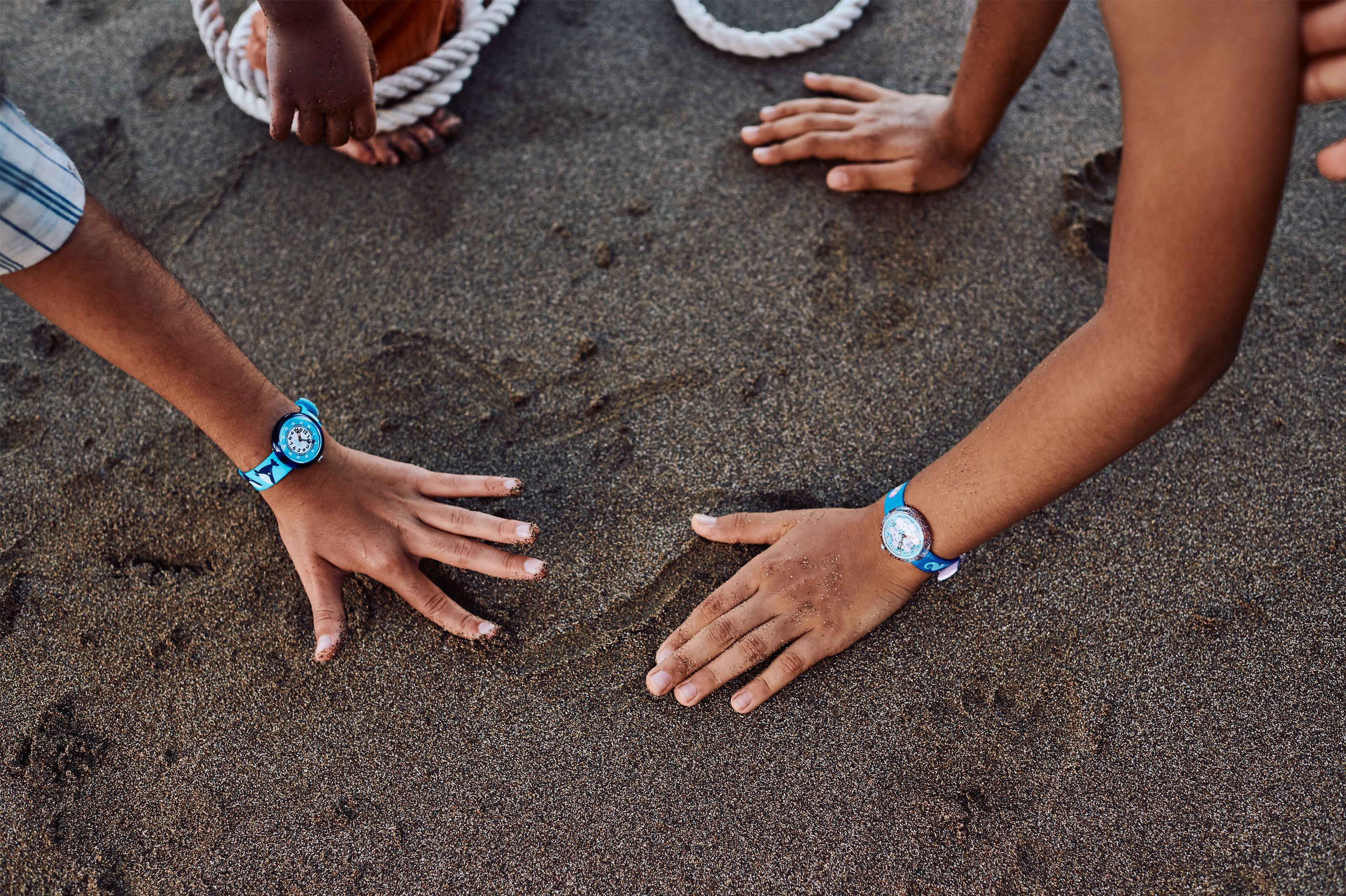 Kids wearing Flik Flak watches touching the sand on the beach