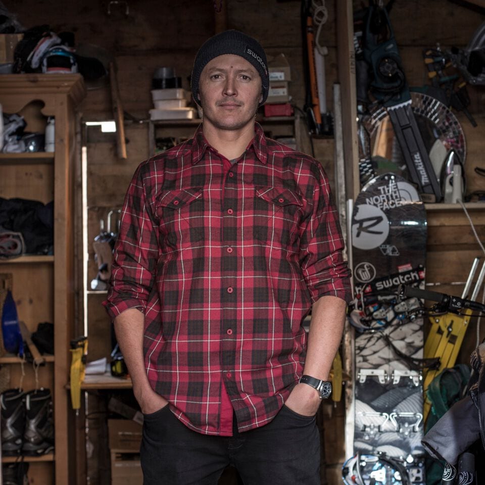 Xavier De Le Rue posing with his snowboard in the background